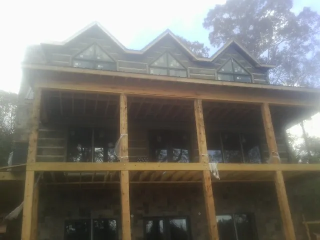 Dormers and porch framing on a large log home under construction — Roof Coating work by our crew in Kenyon