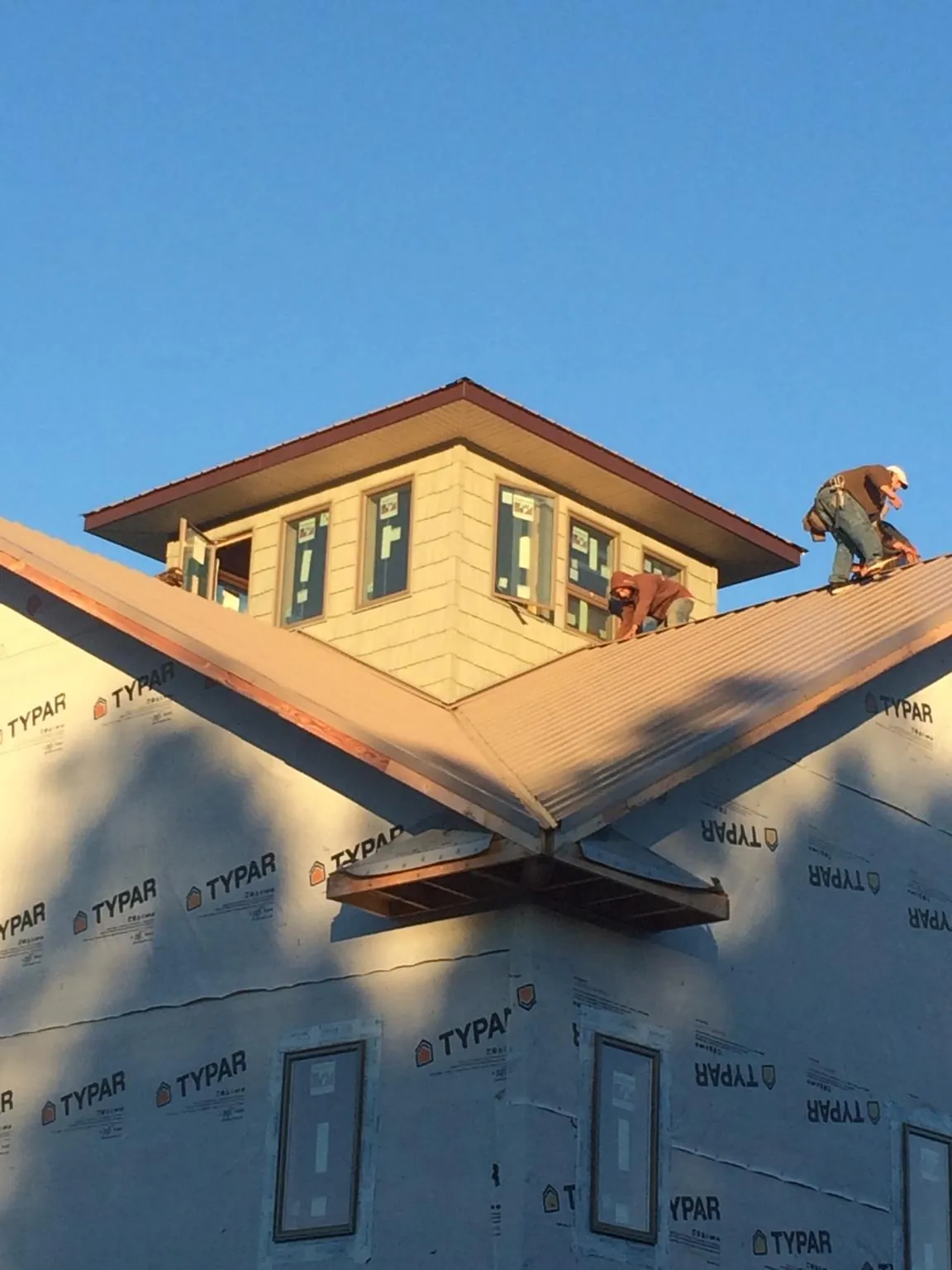 Roofers working around a rooftop cupola on a new metal roof at sunset — Roof Waterproofing in Kenyon by Roofing Brothers